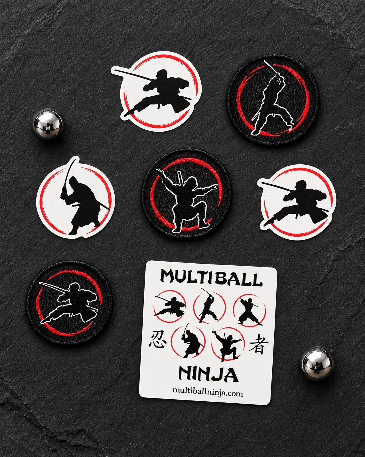 Concept mockup of die-cut stickers and embroidered patches with ninja-in-red-ring marks, laid on slate with two steel pinballs